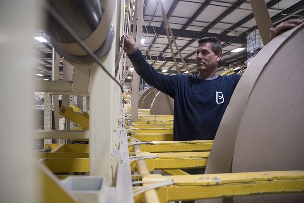 Badger employee watches as manufactured chipboard comes off roll